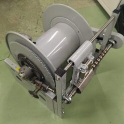 En Slangvinda modell För 50m Ø2" slang- Motordriven 24VDC rulle står på ett bord i ett rum.